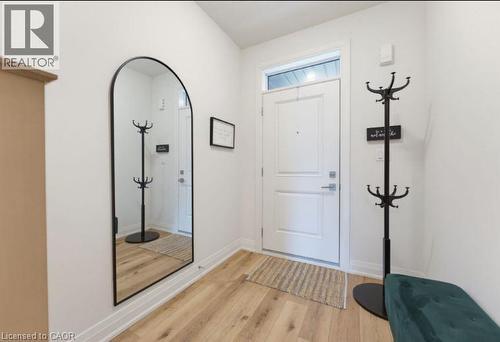 Front entry featuring a white paneled door with transom window, light wood-finish flooring, and white baseboards - 16 Raspberry Lane, Hamilton, ON - Indoor Photo Showing Other Room