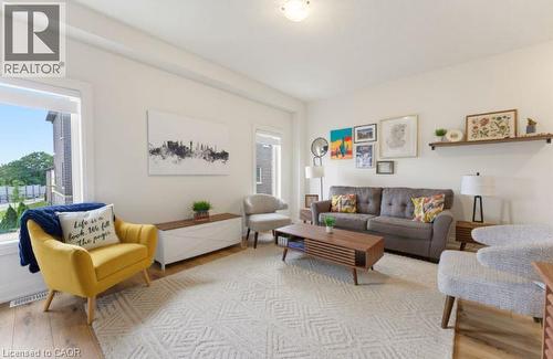 Open-concept living area featuring light wood-finish flooring, a neutral patterned area rug, and white walls - 16 Raspberry Lane, Hamilton, ON - Indoor Photo Showing Living Room