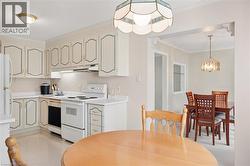 Kitchen featuring light cabinetry, white appliances, a built-in dishwasher, and ample counter space - 