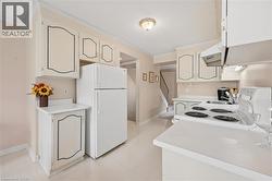 Kitchen featuring white cabinetry with decorative trim, white appliances including an electric range and refrigerator, and a recessed sink - 