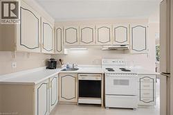 Kitchen featuring white cabinetry with decorative blue trim, white countertops, an undermount sink, and white appliances including a range and dishwasher - 