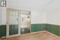 Interior room featuring wood-finish flooring, white walls, and green beadboard wainscoting - 