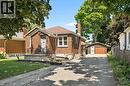 Brick residence featuring a covered front porch with iron railings, a detached garage, an asphalt driveway, and a manicured lawn - 714 Frederick Street, Kitchener, ON  - Outdoor 