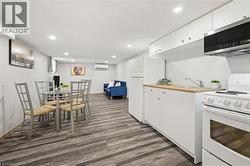 Open-concept living area featuring wood-finish flooring, recessed lighting, a white kitchen with wood countertops, and a built-in microwave - 