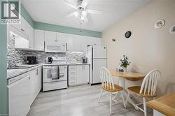 Kitchen featuring white cabinetry, a mosaic tile backsplash, wood-finish flooring, and a ceiling fan - 
