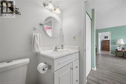 Bathroom vanity featuring a white cabinet with paneled doors and drawers, a white countertop, and a round mirror with chrome light fixture - 