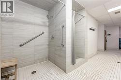 Spacious shower stall with large format wall tiling, a rain showerhead, and grab bars - 