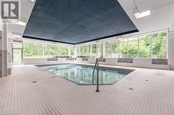 Indoor swimming pool featuring a rectangular shape with an angled corner, surrounded by extensive white grid-patterned floor tiling - 
