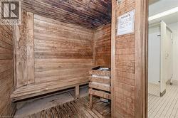 Wood-paneled sauna featuring a built-in bench, a dedicated heater, and wood-finish flooring - 