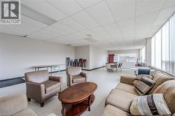 Spacious common area featuring durable flooring, extensive natural light from large windows, and a built-in kitchenette with white cabinetry - 