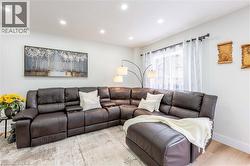 Recessed ceiling lighting illuminates this living space, featuring light-toned walls and wood-finish flooring - 