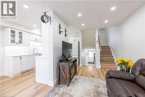 Open-concept living space featuring wood-finish flooring, recessed lighting, and a white kitchen with shaker-style cabinetry and a stainless steel sink - 185 Highland Crescent Unit# 2, Kitchener, ON - Indoor Photo Showing Living Room
