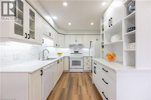 Contemporary kitchen featuring white cabinetry, light countertops, wood-finish flooring, a white tile backsplash, and recessed lighting - 185 Highland Crescent Unit# 2, Kitchener, ON - Indoor Photo Showing Kitchen