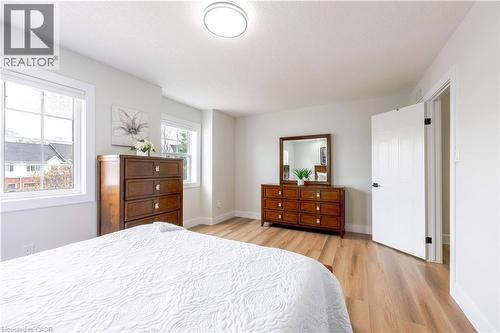 Room featuring light wood-finish flooring, two large windows with white trim, a flush-mount ceiling light fixture, and a white panel door - 185 Highland Crescent Unit# 2, Kitchener, ON - Indoor Photo Showing Bedroom