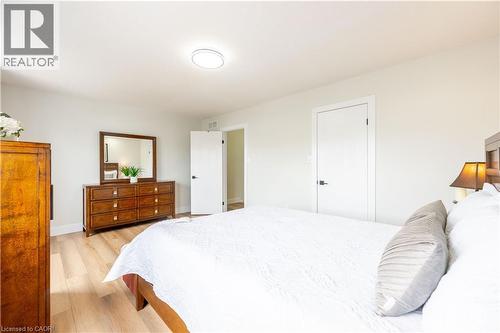 Spacious room featuring light-toned wood-finish flooring, white walls, a flush-mount ceiling light fixture, and white interior doors with dark hardware - 185 Highland Crescent Unit# 2, Kitchener, ON - Indoor Photo Showing Bedroom