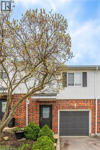 Brick and siding exterior featuring an attached garage with a panel door - 185 Highland Crescent Unit# 2, Kitchener, ON - Outdoor