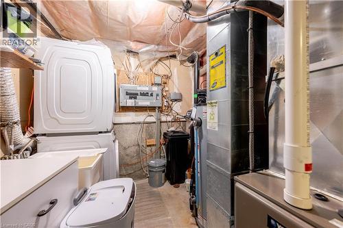Utility area featuring stacked laundry appliances, an electrical service panel, and HVAC system components - 185 Highland Crescent Unit# 2, Kitchener, ON - Indoor Photo Showing Other Room