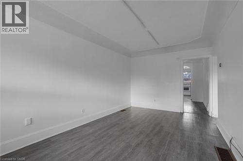 Spacious room featuring light gray wood-finish flooring, white walls, and white trim - 29 Harrison Avenue, Hamilton, ON - Indoor Photo Showing Other Room