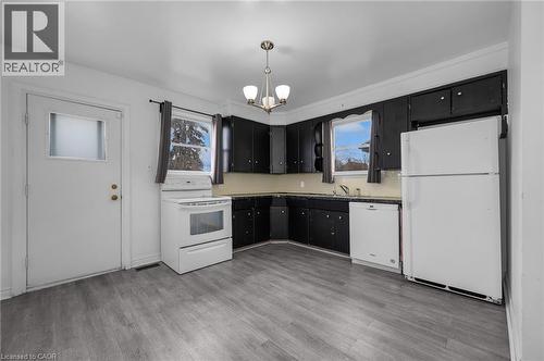 Kitchen featuring dark cabinetry with light countertops, a white refrigerator, and a white oven - 29 Harrison Avenue, Hamilton, ON - Indoor Photo Showing Kitchen