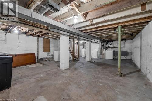 Unfinished basement featuring exposed wood joists, concrete flooring, concrete block walls, and utility hookups - 29 Harrison Avenue, Hamilton, ON - Indoor Photo Showing Basement