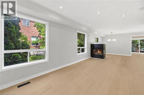 Expansive interior featuring light wood-finish flooring, recessed lighting, and a modern fireplace with a dark surround and light mantel - 5628 Stella Lane, Burlington, ON - Indoor Photo Showing Living Room With Fireplace