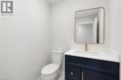 Modern bathroom vanity with a navy blue base, gold-toned hardware, and a white countertop with an integrated sink - 5628 Stella Lane, Burlington, ON - Indoor Photo Showing Bathroom