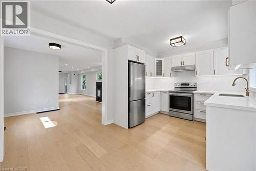 Modern kitchen featuring white cabinetry, stainless steel appliances, light countertops, and wood-finish flooring - 5628 Stella Lane, Burlington, ON - Indoor Photo Showing Kitchen