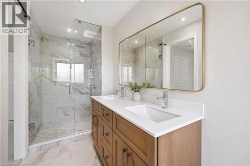 Bathroom featuring a dual-sink vanity with a white countertop, wood-finish cabinetry, and a large framed mirror - 5628 Stella Lane, Burlington, ON - Indoor Photo Showing Bathroom