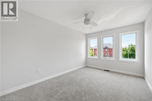 Bright room featuring three large windows, a ceiling fan, light-colored walls, and gray carpet flooring - 5628 Stella Lane, Burlington, ON - Indoor Photo Showing Other Room