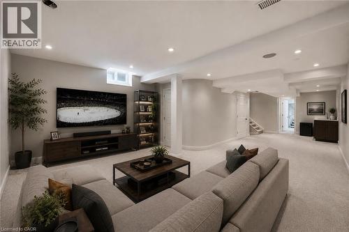 Spacious recreation area featuring plush carpeting, recessed lighting, a built-in media console, an illuminated display shelf, and a wet bar with a dark wood-finish cabinet - 5628 Stella Lane, Burlington, ON - Indoor