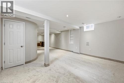 Expansive finished basement featuring recessed lighting, light-toned carpeting, a built-in shelving unit, a window, and a curved architectural wall - 5628 Stella Lane, Burlington, ON - Indoor Photo Showing Basement