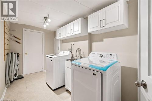Dedicated laundry room featuring light-toned tile flooring, overhead track lighting, and crisp white cabinetry - 5628 Stella Lane, Burlington, ON - Indoor Photo Showing Laundry Room