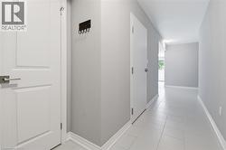 Hallway featuring light gray painted walls, white trim, square tile flooring, and white paneled doors with brushed nickel hardware - 