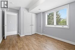Room featuring wood-finish flooring, light grey walls, white baseboards, and white trim - 