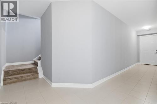Entryway featuring light-toned tile flooring, white baseboards, and a white paneled door with brushed metal hardware - 5 Hagar Street, Thorold, ON - Indoor Photo Showing Other Room