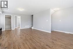 Spacious room featuring wood-finish flooring, light gray wall paint, and white baseboards - 