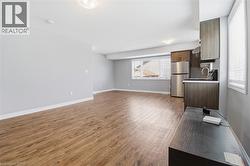 Open-concept living space featuring wood-finish flooring, light gray wall tones, and recessed lighting - 