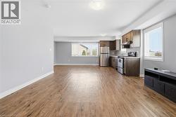 Open-concept living space featuring wood-finish flooring, light grey walls, and white trim - 