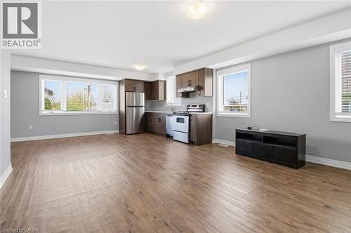 Open-concept living space featuring wood-finish flooring, a full kitchen with stainless steel appliances and dark wood cabinetry, and multiple windows with white blinds - 5 Hagar Street, Thorold, ON - Indoor Photo Showing Kitchen