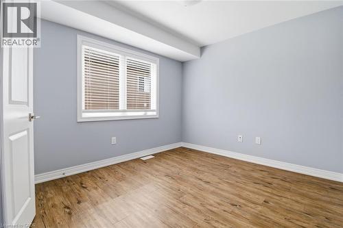 Room featuring wood-finish flooring, a white window with horizontal blinds, light gray wall paint, white baseboards, and a white interior door - 5 Hagar Street, Thorold, ON - Indoor Photo Showing Other Room