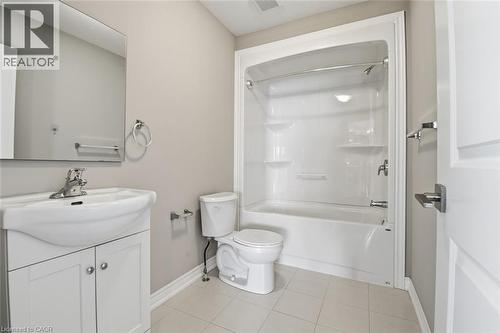 Bathroom featuring a white vanity with integrated sink, rectangular mirror, and a combined bathtub and shower unit - 5 Hagar Street, Thorold, ON - Indoor Photo Showing Bathroom