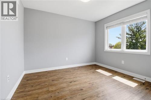 Spacious room featuring wood-finish flooring, light grey walls, and white baseboards - 5 Hagar Street, Thorold, ON - Indoor Photo Showing Other Room