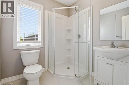 Bathroom featuring a corner shower with glass enclosure, white vanity with integrated sink, chrome faucet, and a toilet - 5 Hagar Street, Thorold, ON - Indoor Photo Showing Bathroom