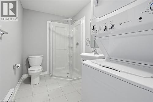 Compact bathroom featuring a corner glass-enclosed shower, pedestal sink, and a stacked washer and dryer unit - 5 Hagar Street, Thorold, ON - Indoor