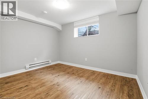 Room with wood-finish flooring, light grey walls, white baseboards, and a window with white blinds - 5 Hagar Street, Thorold, ON - Indoor Photo Showing Other Room