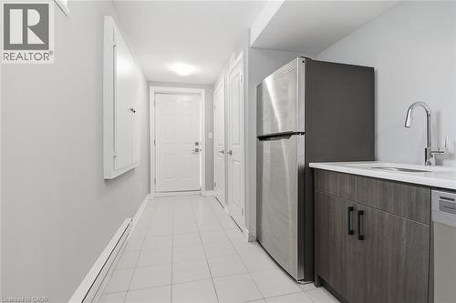 Stainless steel refrigerator with a light wood-finish lower cabinet, a single-basin sink, and a chrome gooseneck faucet - 5 Hagar Street, Thorold, ON - Indoor