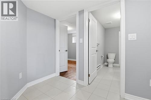 Interior hallway featuring light gray walls, white trim, and square tile flooring - 5 Hagar Street, Thorold, ON - Indoor