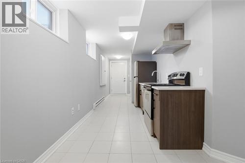Kitchenette featuring stainless steel appliances, dark wood-finish cabinetry, light-toned countertops, and a stainless steel range hood - 5 Hagar Street, Thorold, ON - Indoor Photo Showing Kitchen