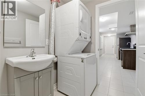 Laundry area featuring a stackable washer and dryer, a vanity with a ceramic sink, and a framed mirror - 5 Hagar Street, Thorold, ON - Indoor Photo Showing Other Room