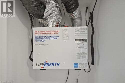 Energy-efficient heat recovery ventilator unit with visible ductwork and wiring, installed within white walls - 5 Hagar Street, Thorold, ON - Indoor Photo Showing Basement